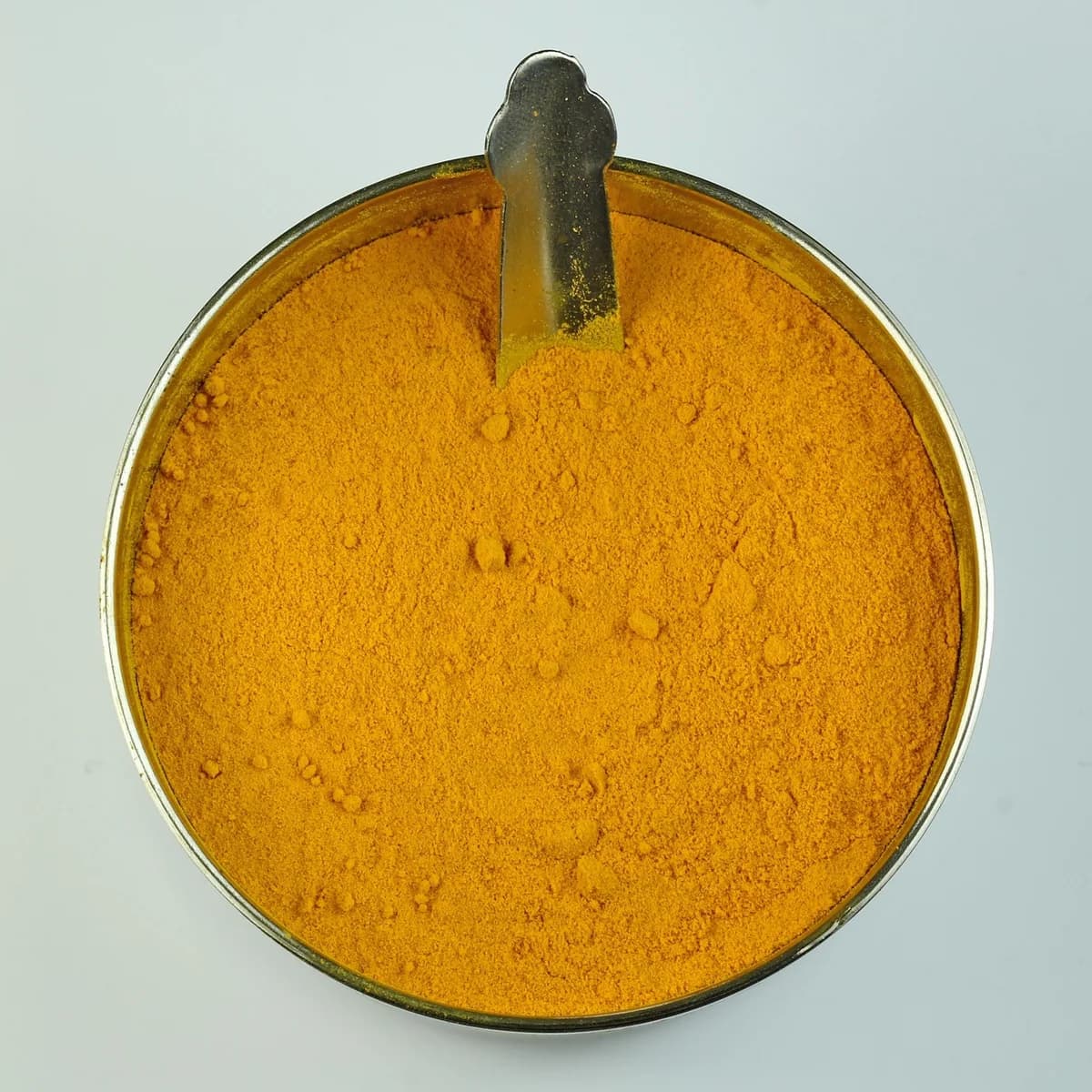 Pure Indian turmeric powder in a bowl with whole turmeric roots