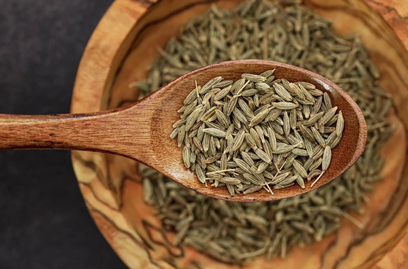Wooden sampling scoop of graded whole cumin seeds